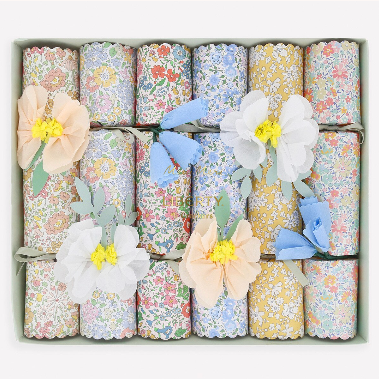 Decorative gift wrap rolls with floral patterns and flower embellishments in a box.