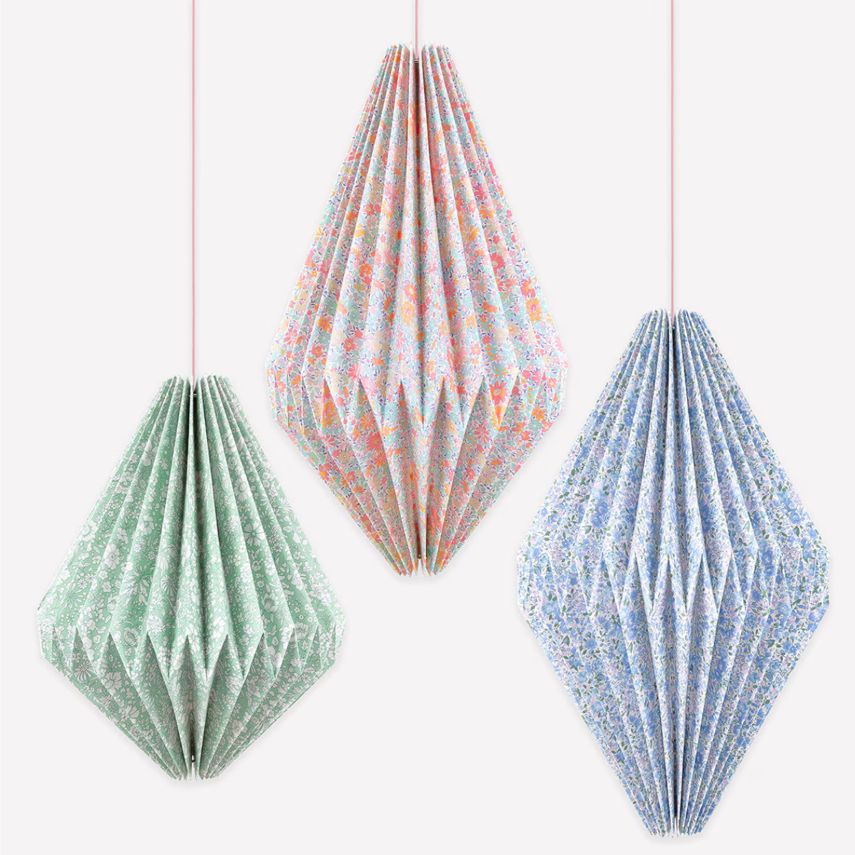 Three diamond-shaped paper decorations in green, pink, and blue on a white background