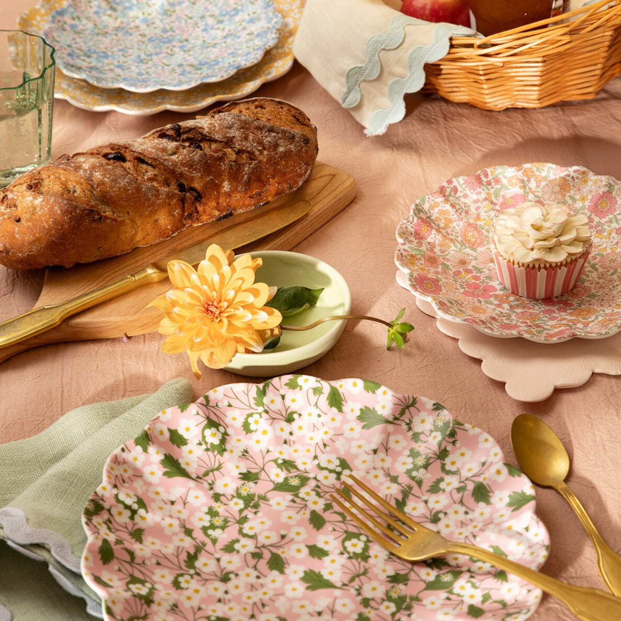 Table setting with floral plates, bread, and a cupcake.