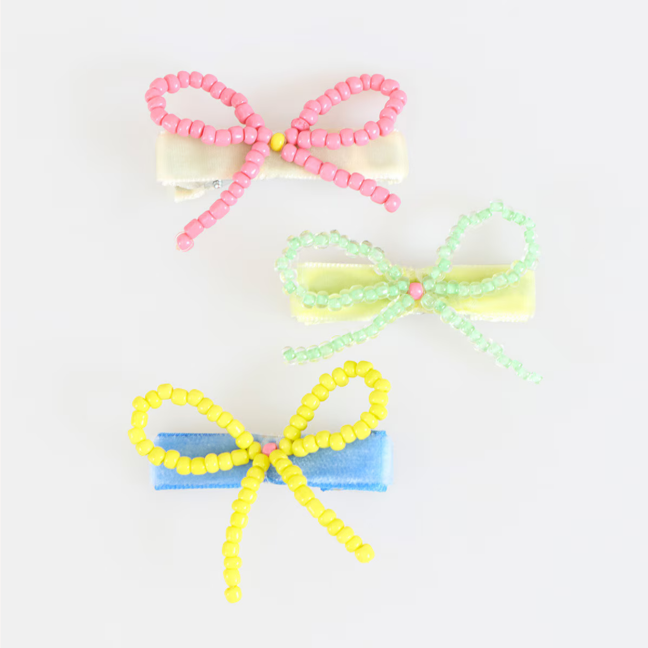 Three colorful beaded bow hair ties on a white background