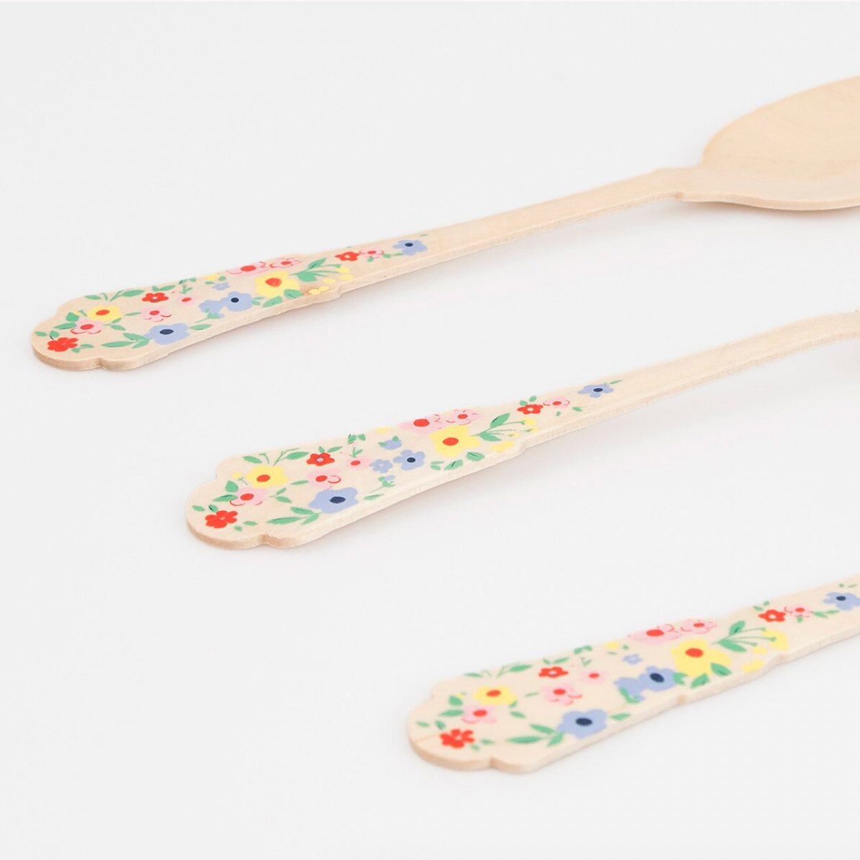 Three wooden spoons with floral patterns on a white background