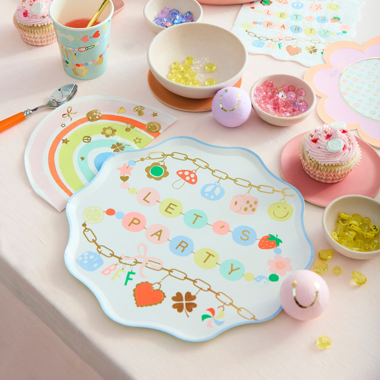 Children's party table setup with colorful plates, cups, and decorations on a white surface.