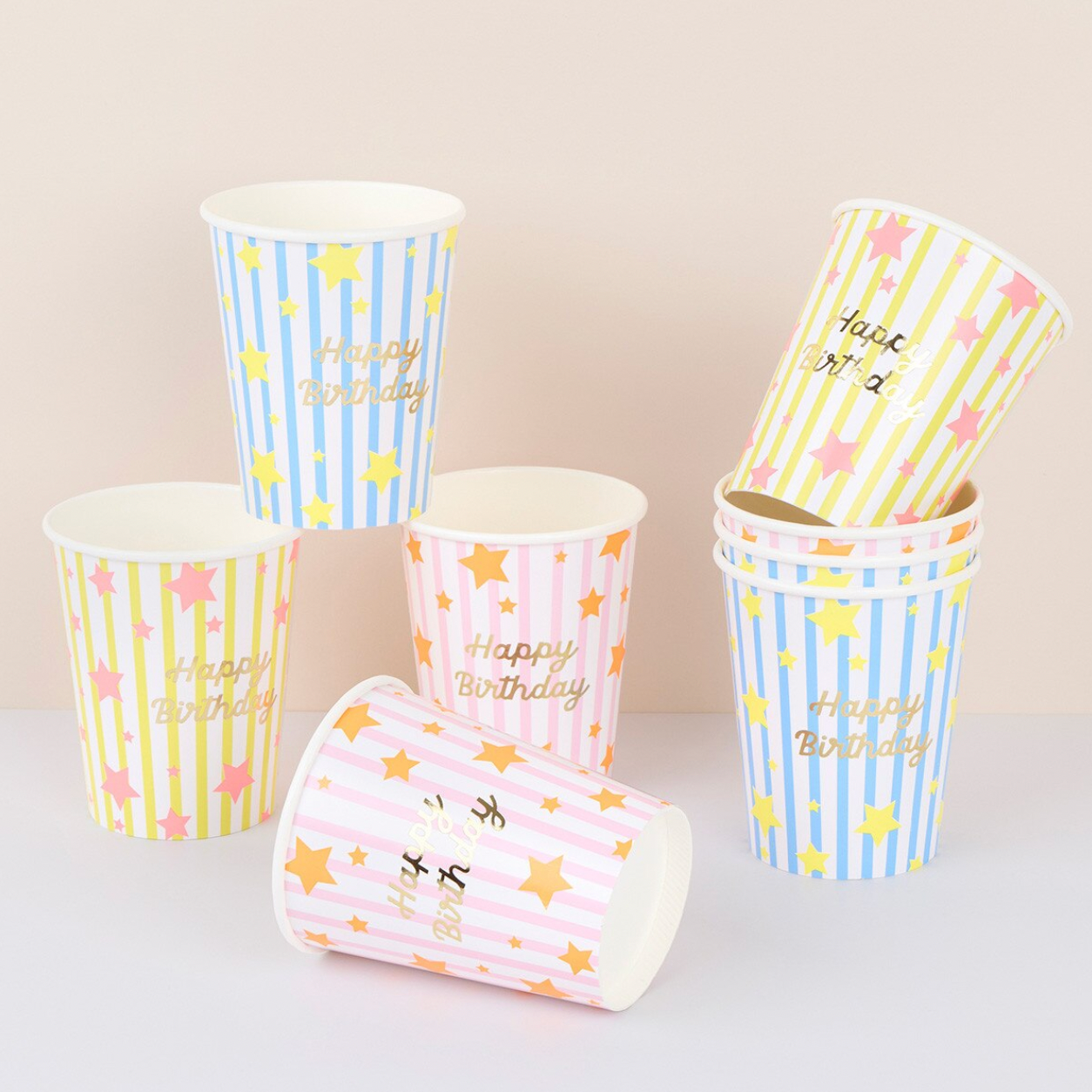 Set of paper cups with 'Happy Birthday' text and star designs on a light background