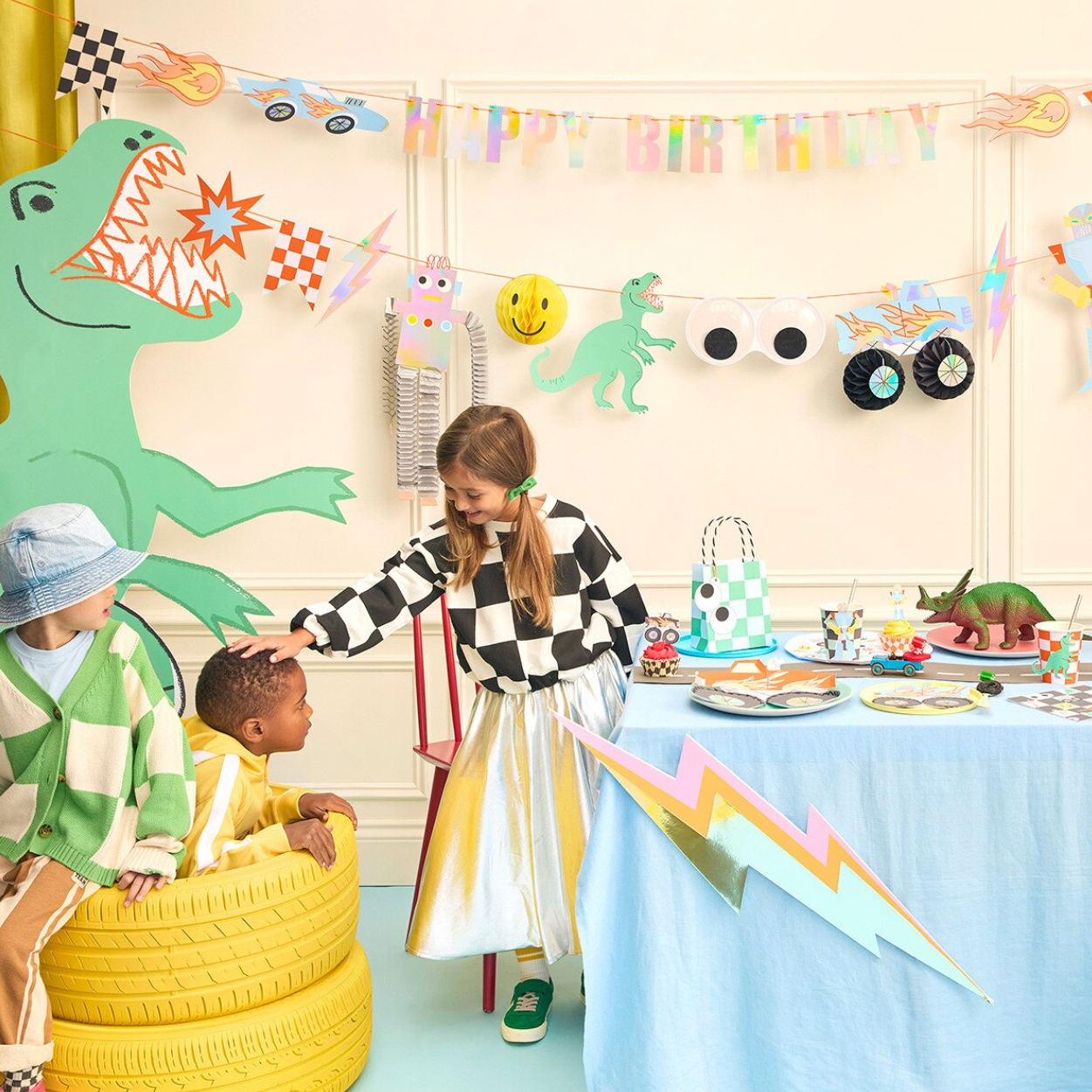 Children at a birthday party with dinosaur-themed decorations and a table set for a meal.