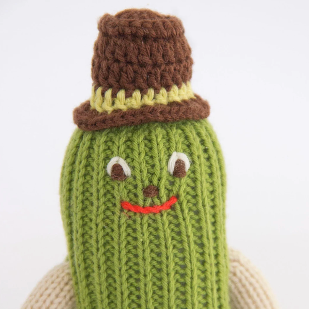 Knitted pickle toy with a brown hat on a white background