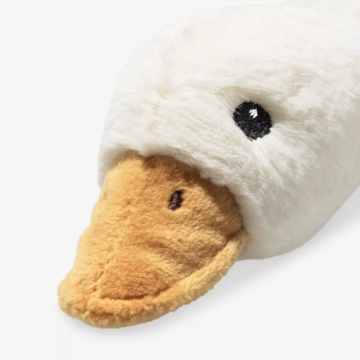 Close-up of a plush duck toy with a white face, brown beak, and black eyes on a white background.