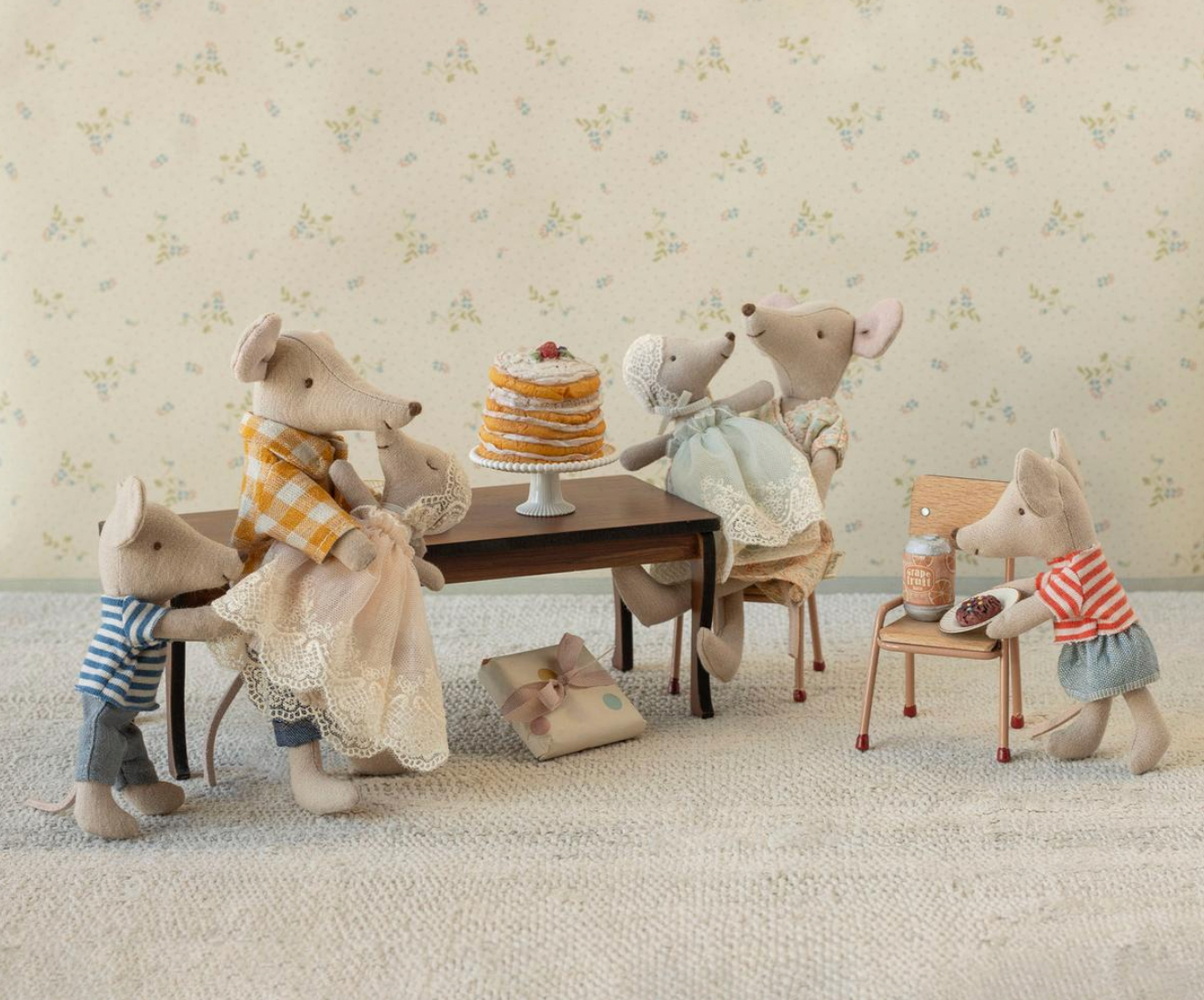 Toy mice with a cake and table setting on a floral wallpaper background