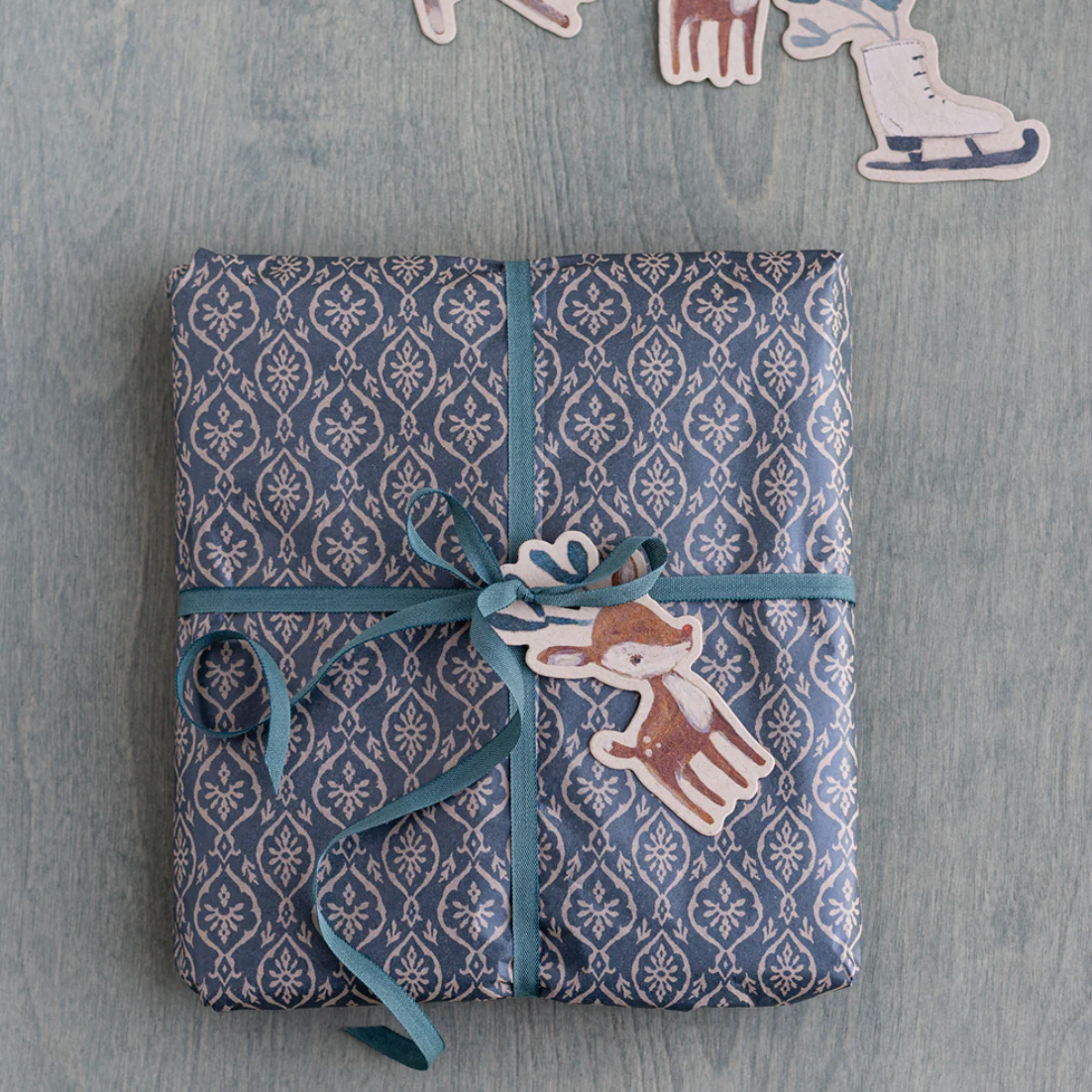 Packaged product with blue ribbon and decorative label on a gray surface