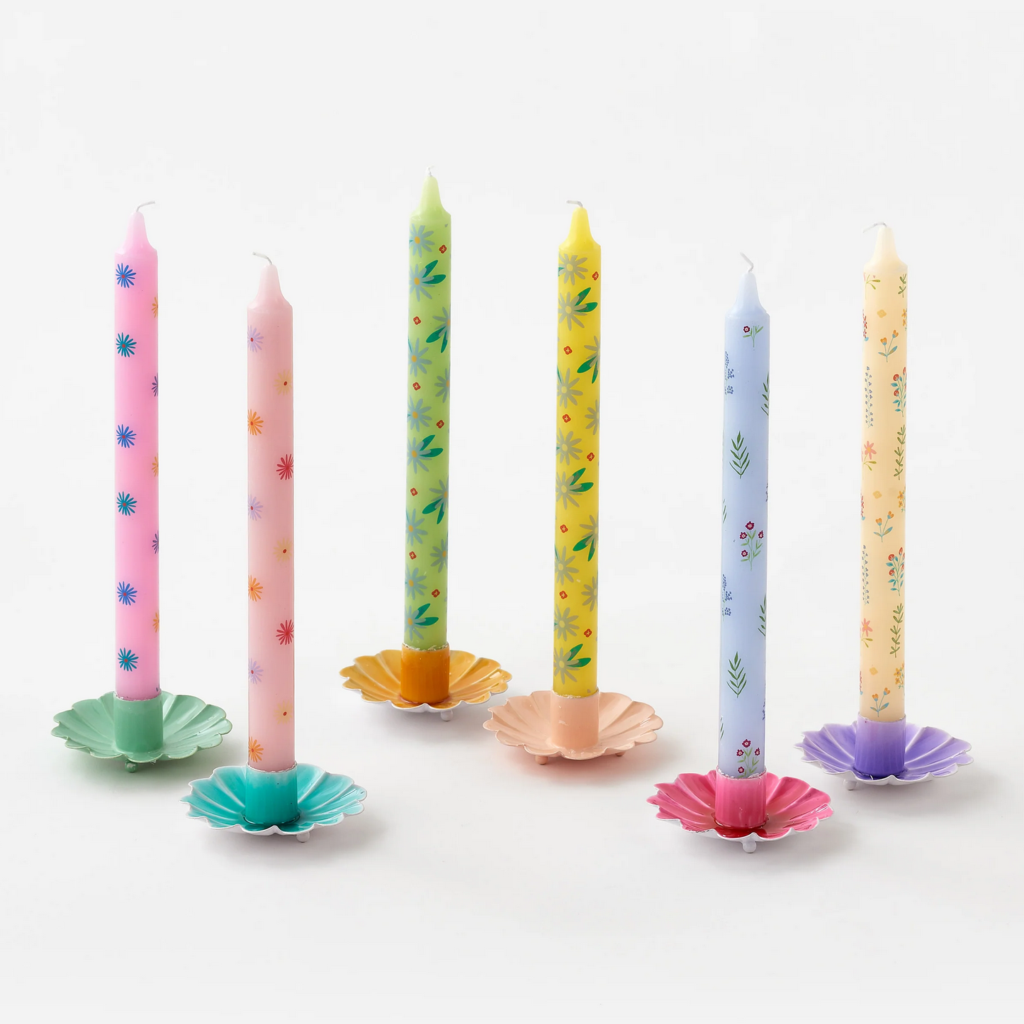 Set of colorful birthday candles with decorative holders on a white background