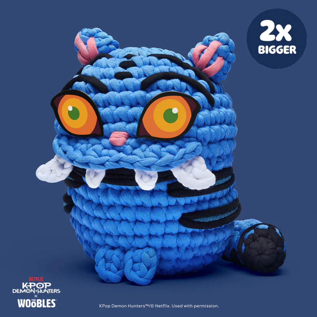 Blue plush toy with large eyes and a '2x Bigger' label on a blue background