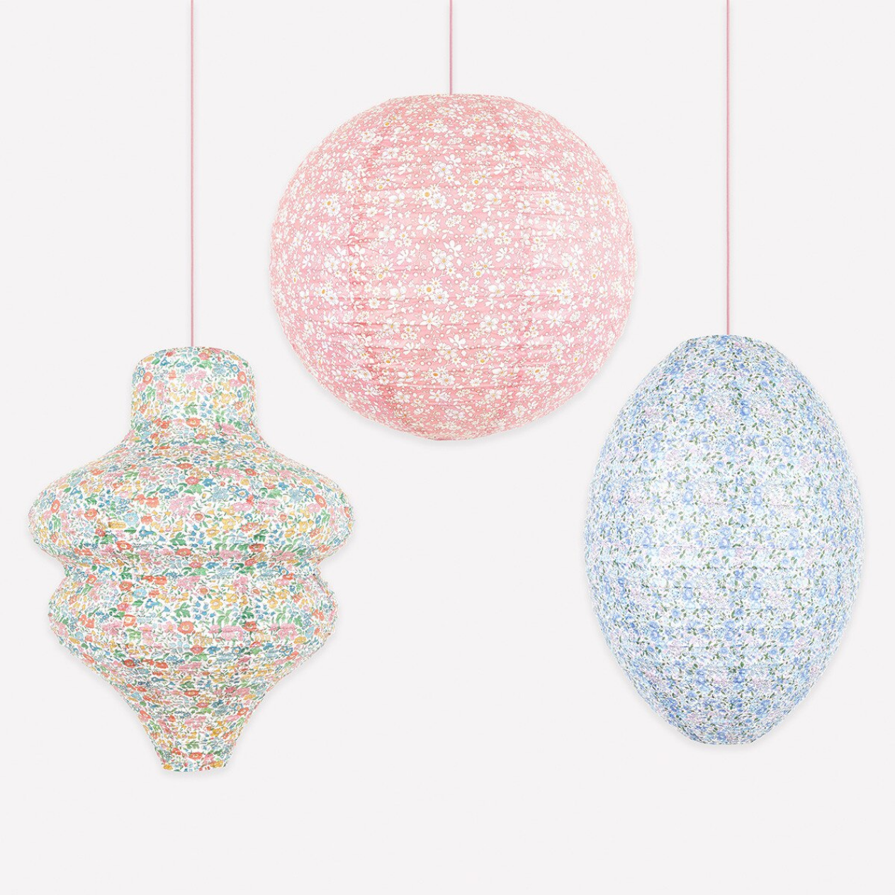Three colorful, textured hanging objects on a white background