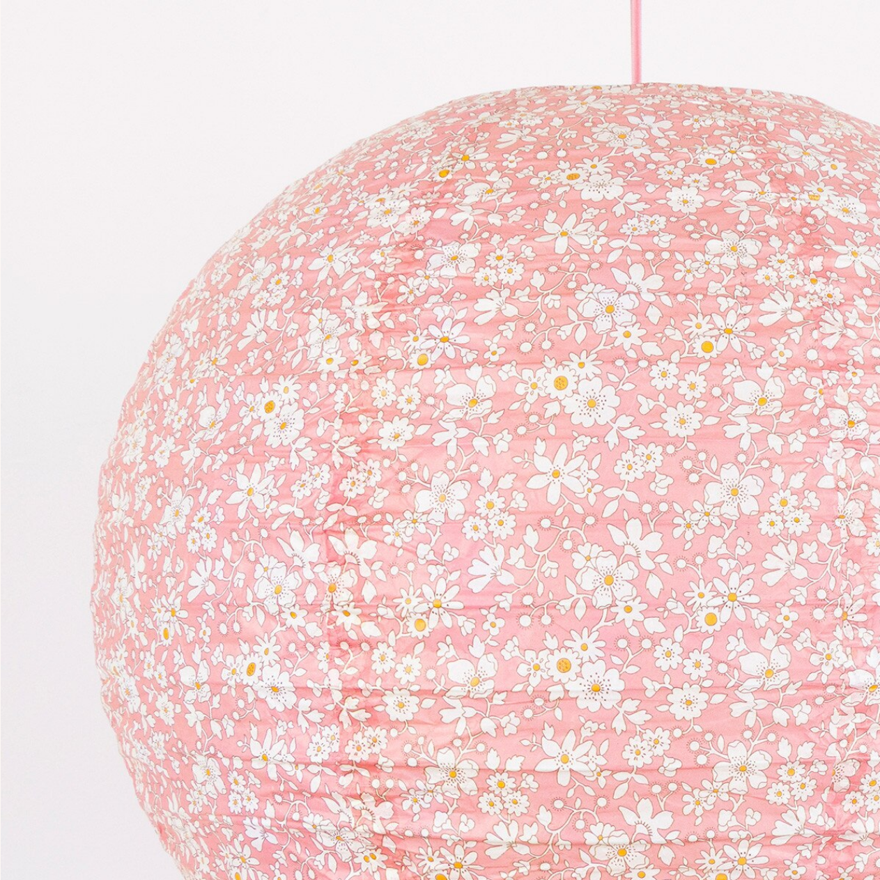 Floral-patterned pink lampshade on a white background