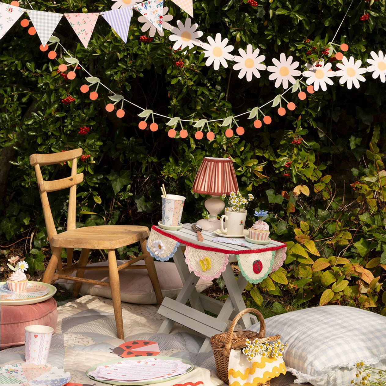 Outdoor setting with a small table, chair, and decorative elements against a green hedge.