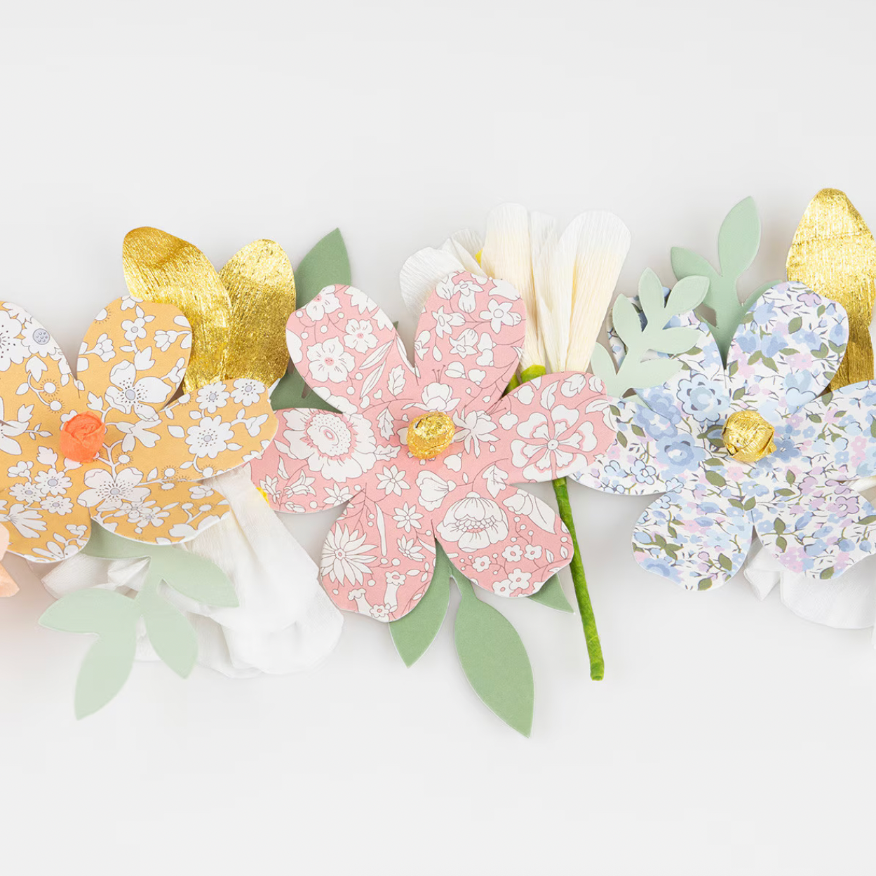 Decorative paper flowers in pastel and gold colors on a white background