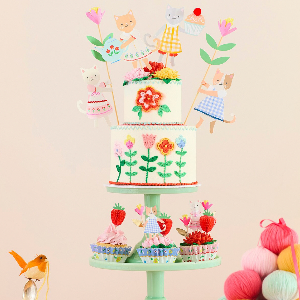 Decorative cake with animal figures and flowers on a stand against a beige background