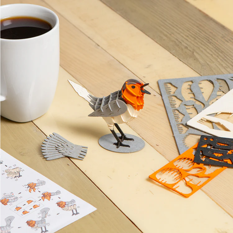 Bird-shaped puzzleon a wooden surface with a cup of coffee and pieces in the background.