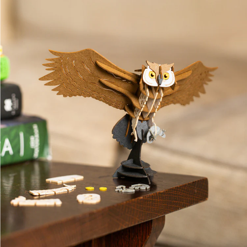 Wooden owl figurine with open wings on a wooden surface