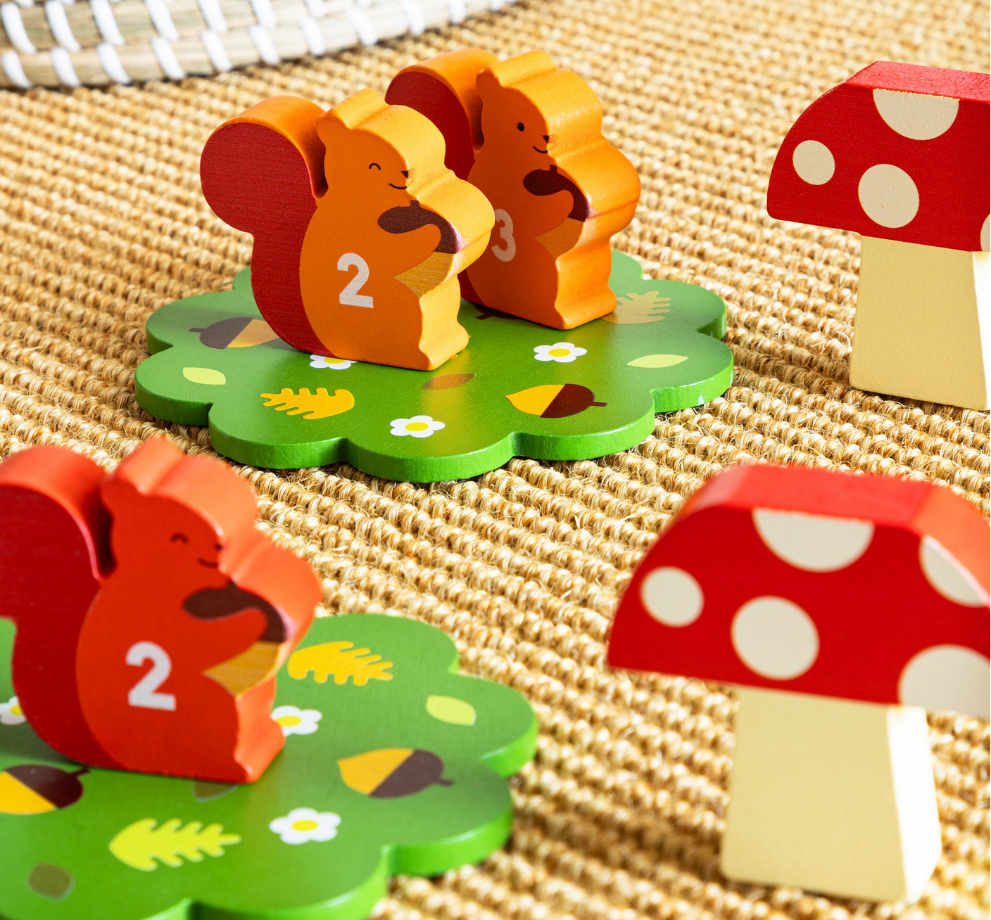 Wooden animal figures with numbers on a textured surface, surrounded by red and white mushroom decorations.
