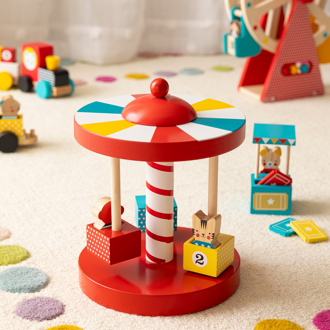 Colorful toy carousel with moving parts on a carpeted floor with other toys in the background.