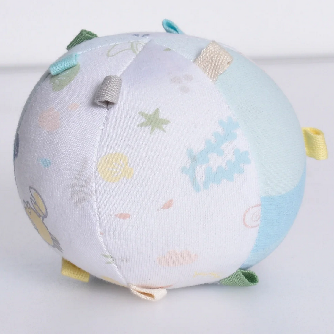 Round soft toy with colorful patterns on a light background