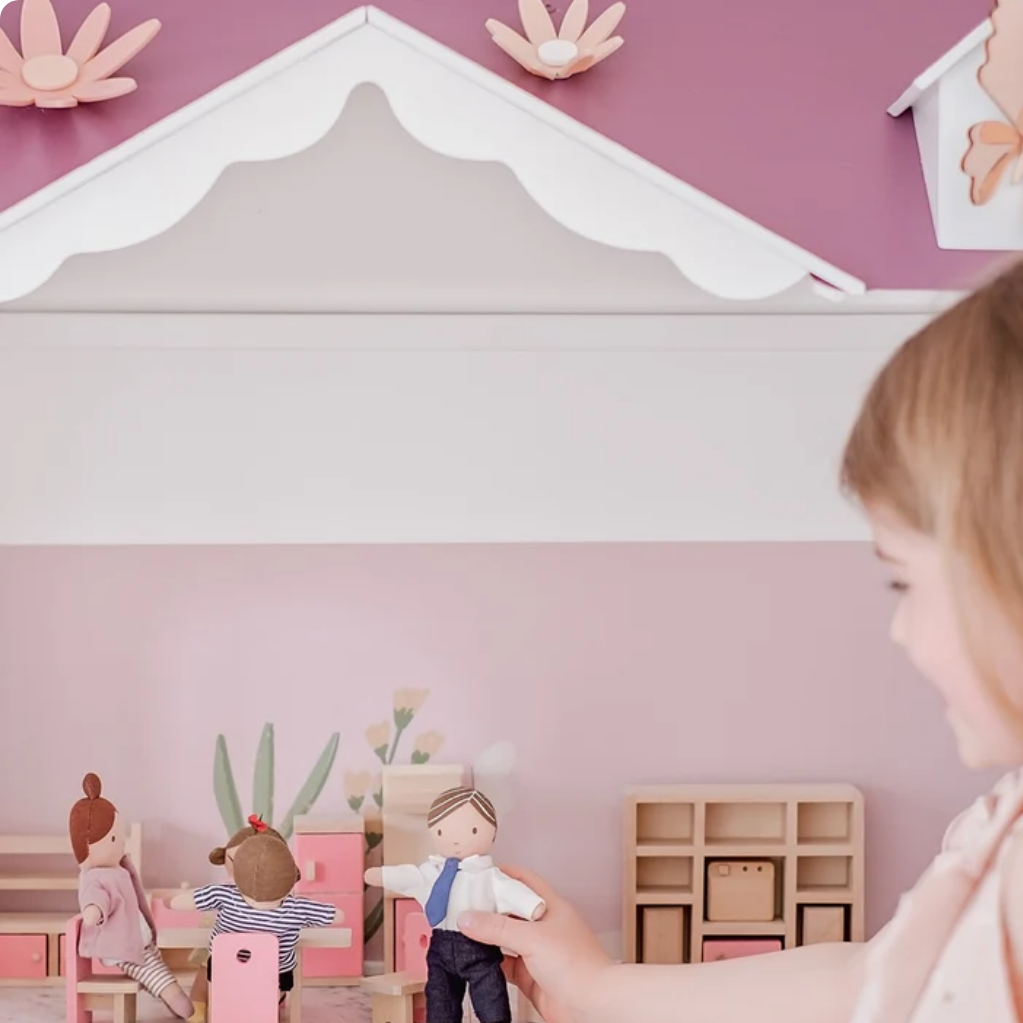 Child playing with toy figures in a miniature room setup.