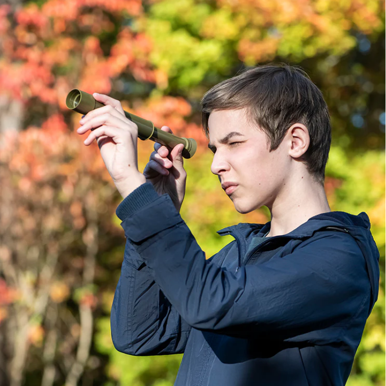 Person using binoculars with a colorful autumn background