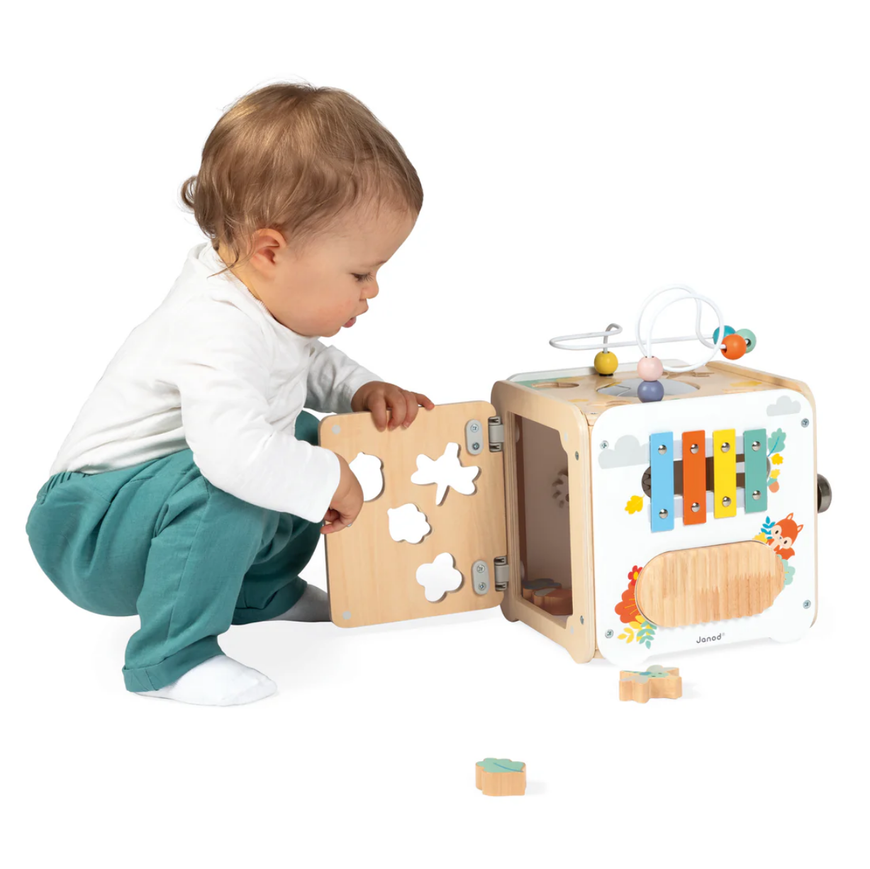 Baby playing with a wooden activity cube on a white background
