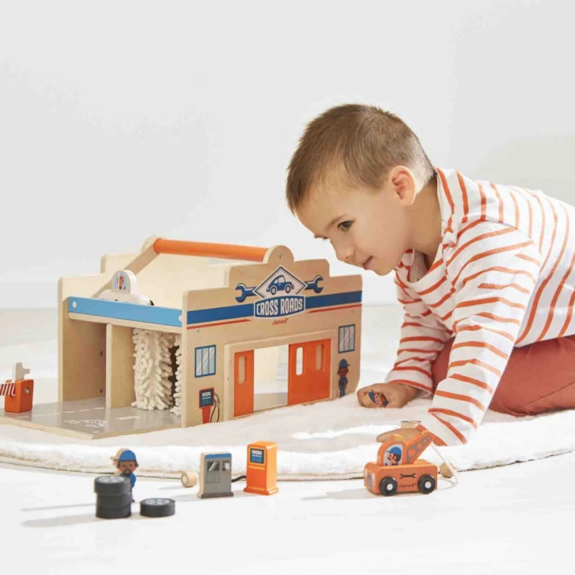 Child playing with toy train set on a white floor