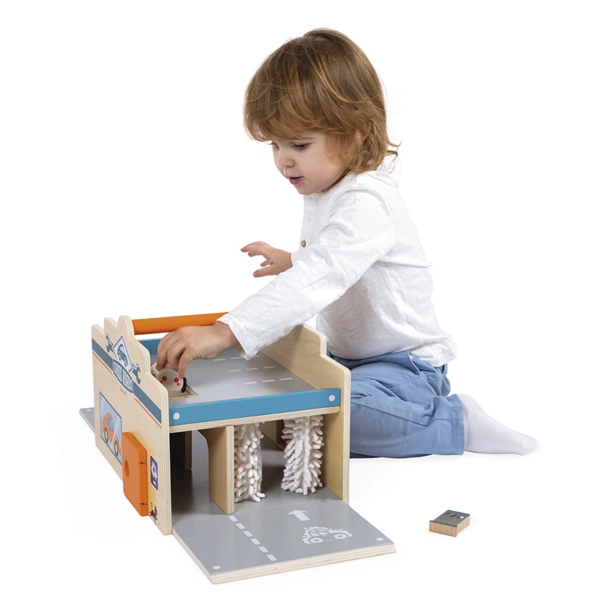 Child playing with a wooden toy garage on a white background