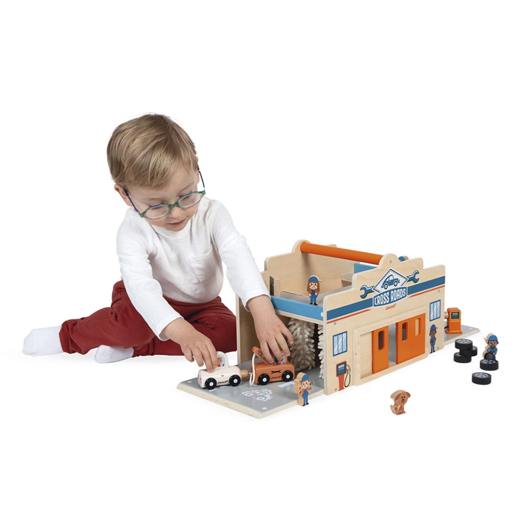 Child playing with a toy garage set on a white background