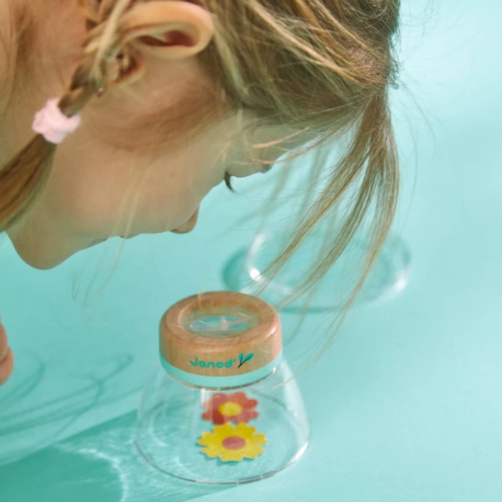 Person with braided hair looking into a clear container with a wooden lid on a light blue background