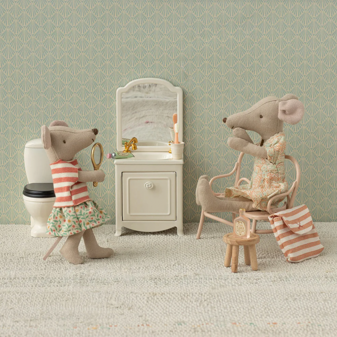 Two toy mice in a bathroom setting with a mirror and sink.