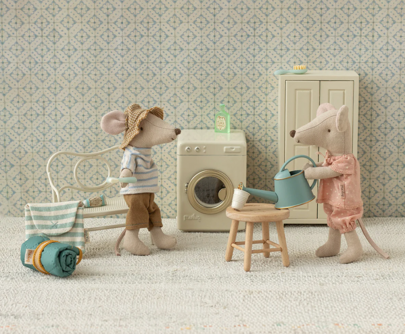 Two toy mice in a room with a washing machine and furniture.