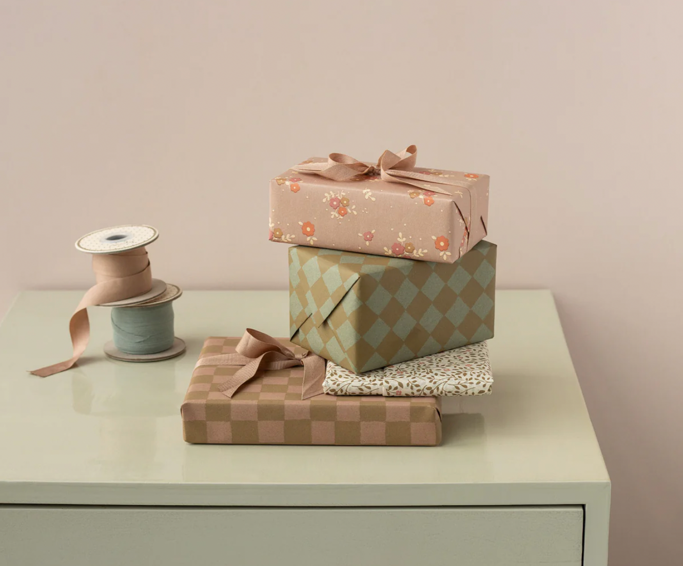 Stack of gift boxes with ribbons on a light surface against a plain background