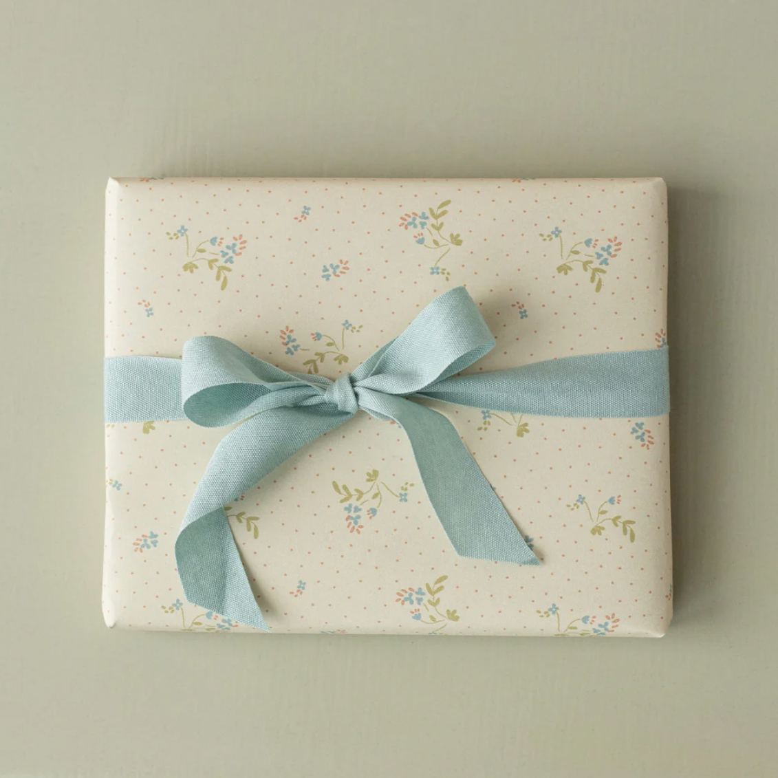 Gift box with floral pattern and blue ribbon on a plain background