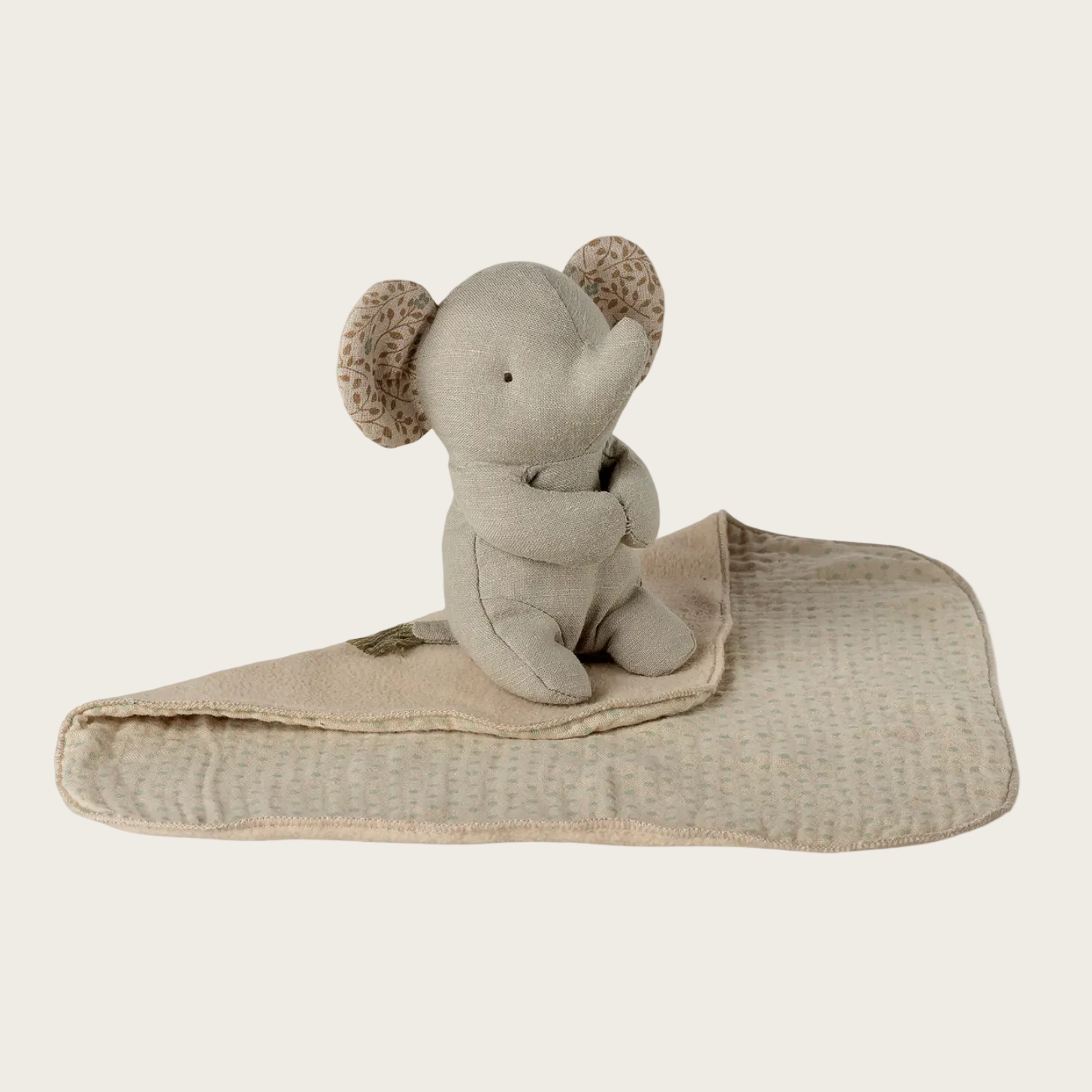 Gray elephant plush toy with a blanket on a website page
