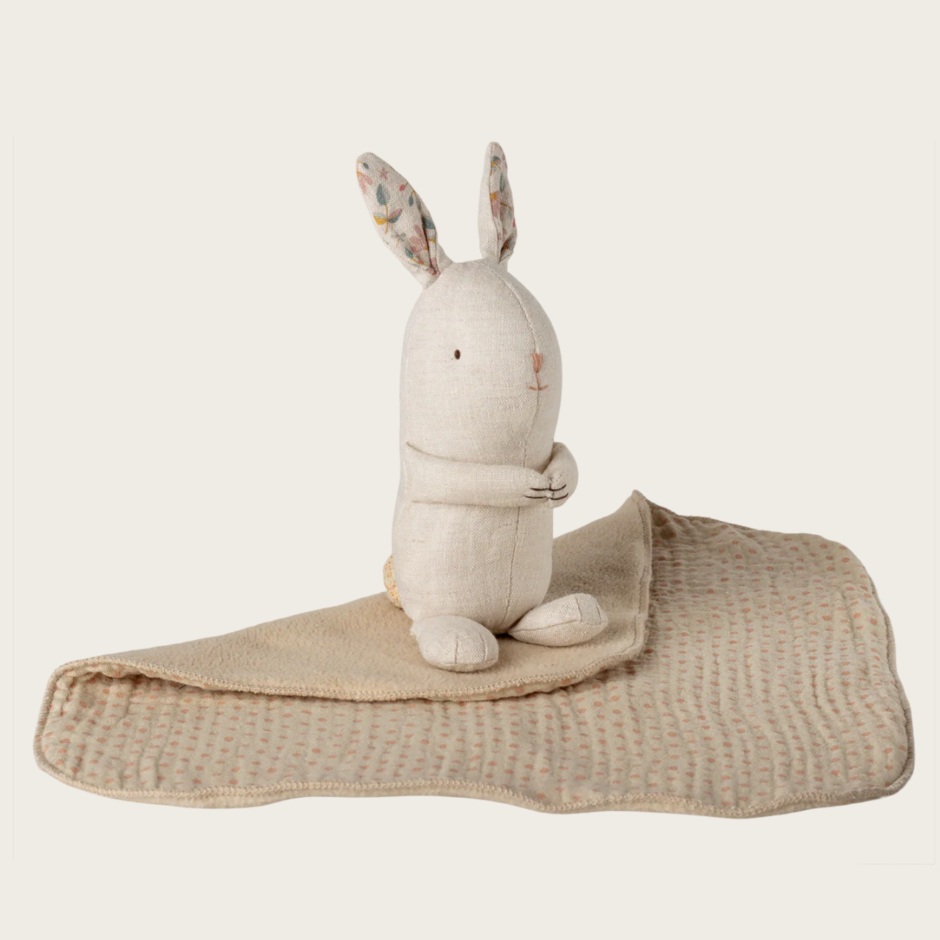White rabbit plush toy with a beige blanket on a website page