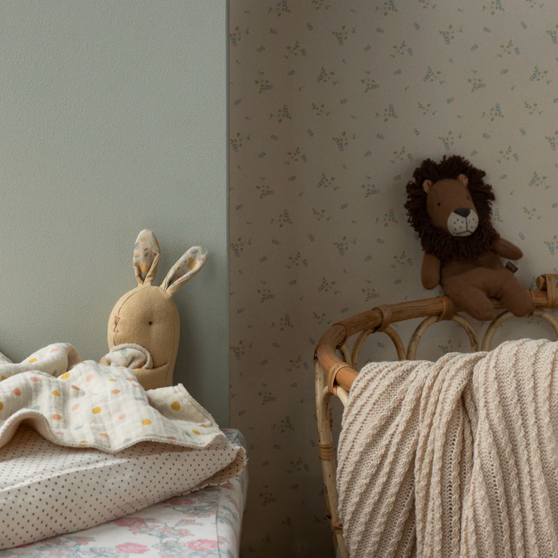Children's room with stuffed lion toy on a chair and rabbit head pillow on a bed.