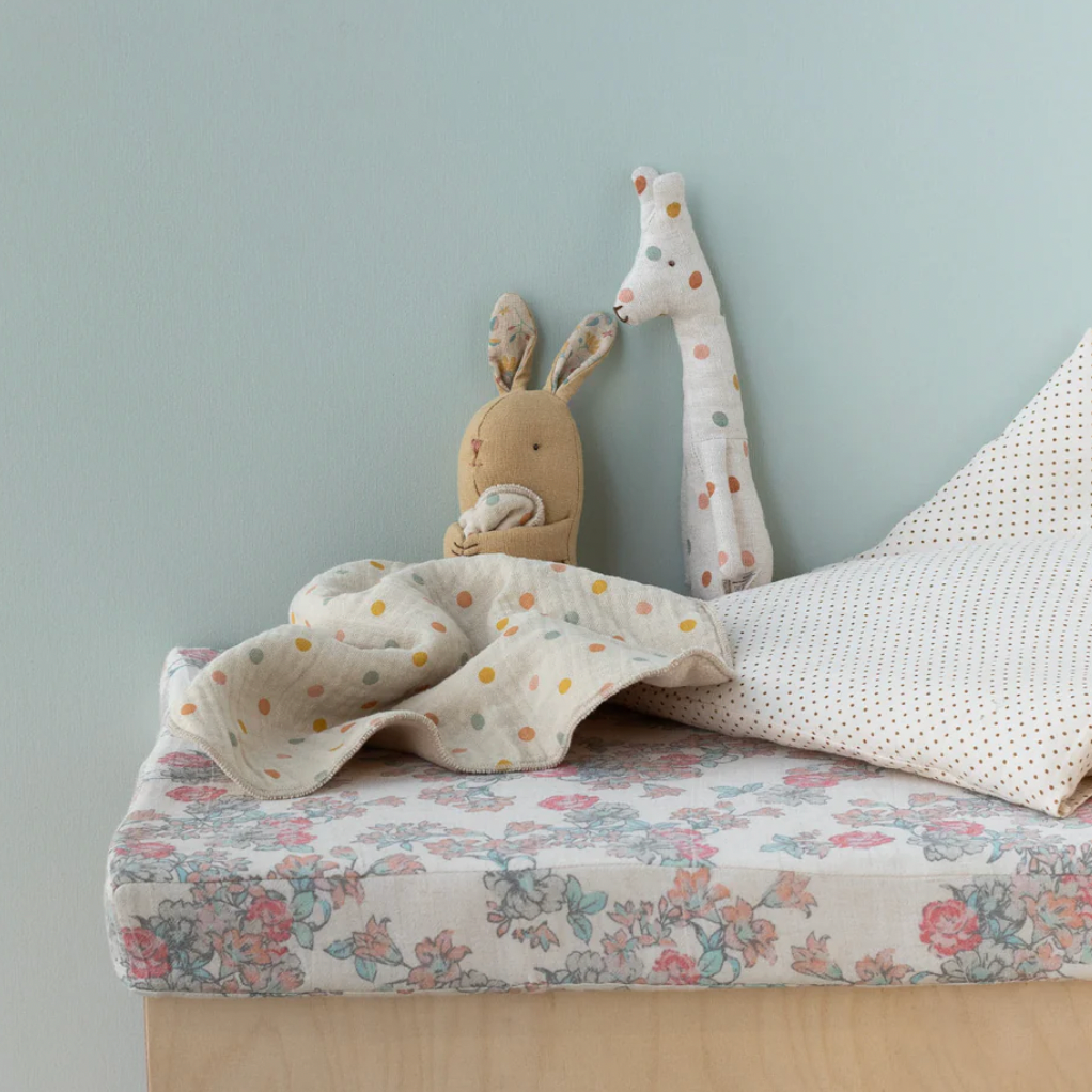 Children's room with a bed, stuffed animals, and a light blue wall.