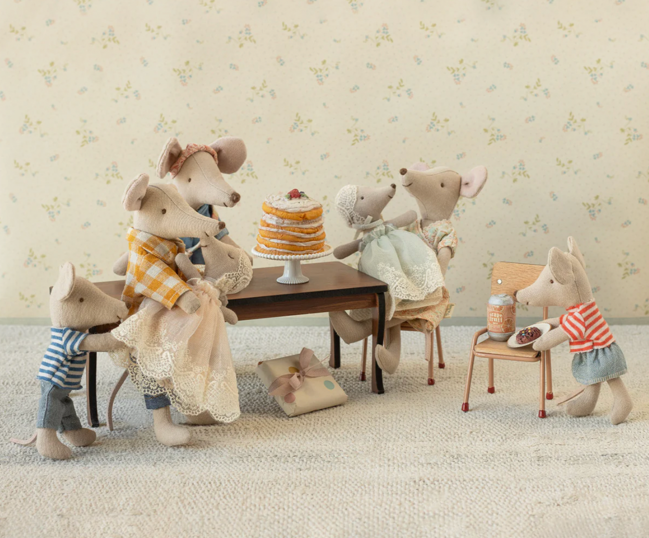 Stuffed animal toy set of mice around a table with a cake on a floral wallpaper background