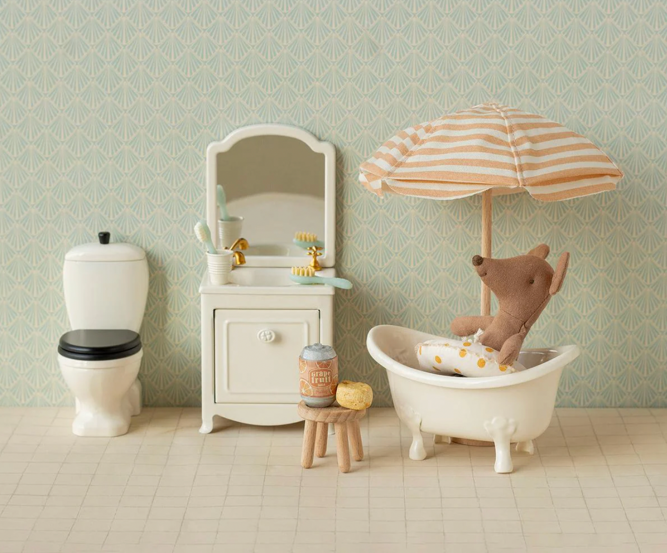Miniature bathroom set with a toy mouse in a bathtub, striped umbrella, and small sink.