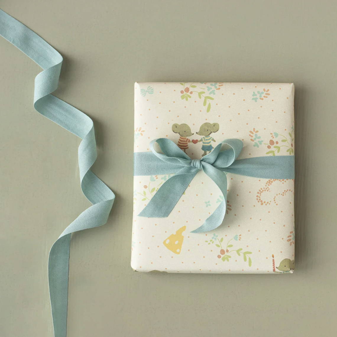 Gift box with floral design and blue ribbon on a beige background