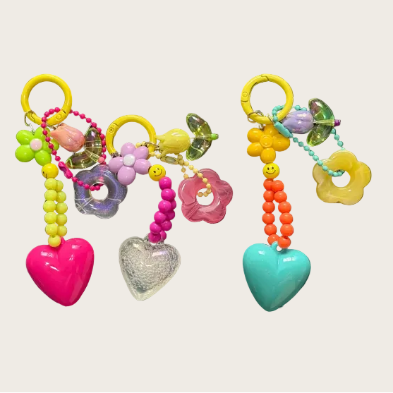 Colorful keychains with heart and flower designs on a white background