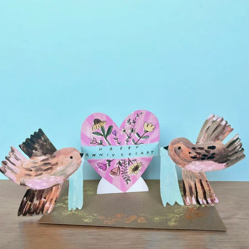 Card with two birds and a heart-shaped card on a light blue background
