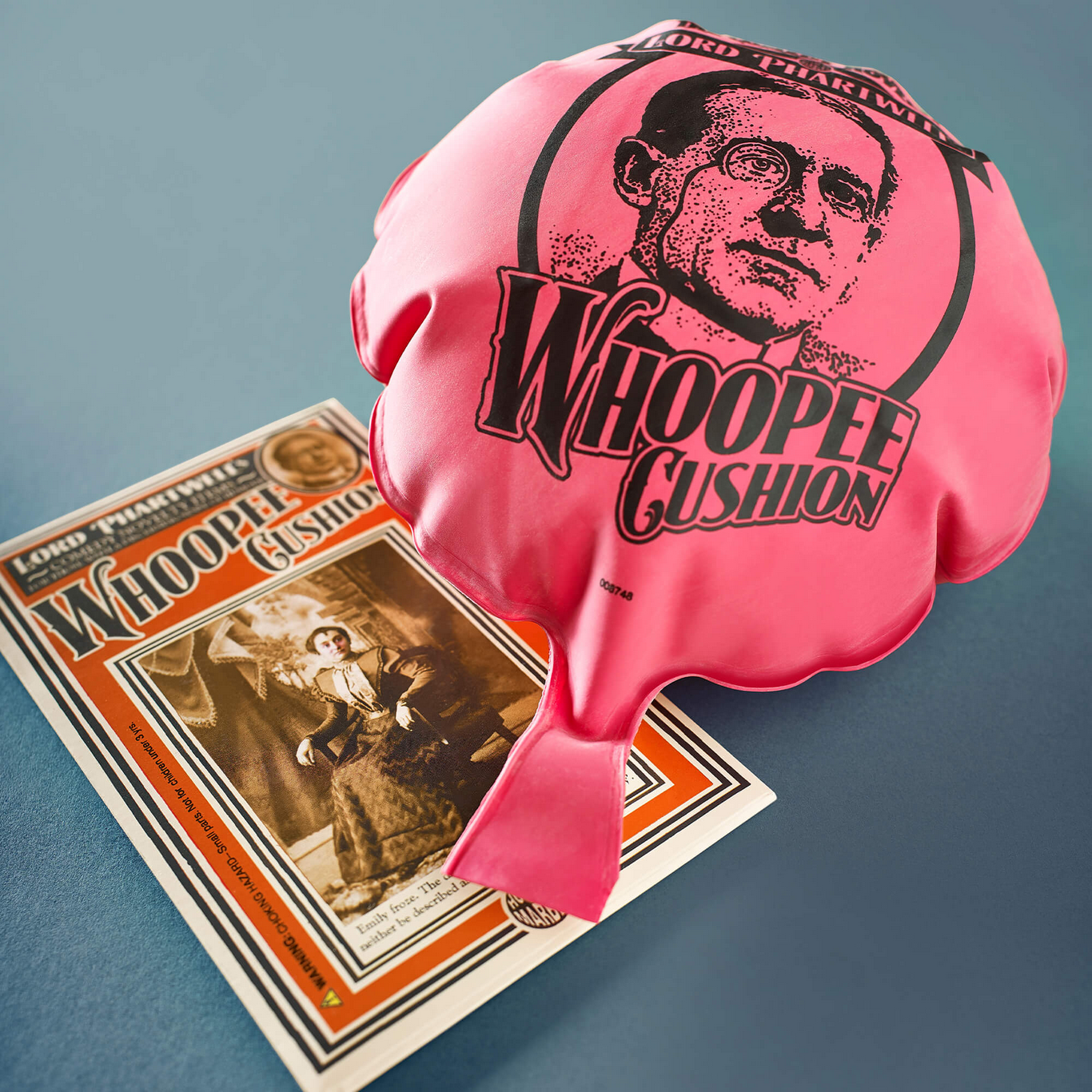Pink whoopee cushion with a vintage-style packaging on a blue background