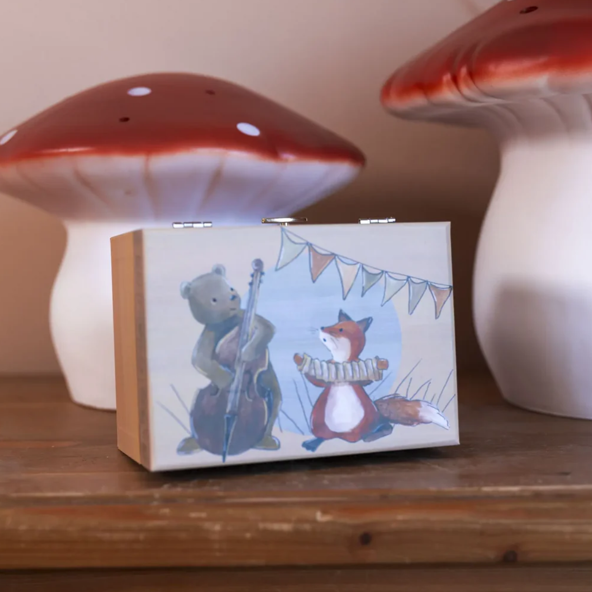 music box with illustration of bear and fox, surrounded by mushroom-shaped lights on a wooden surface.
