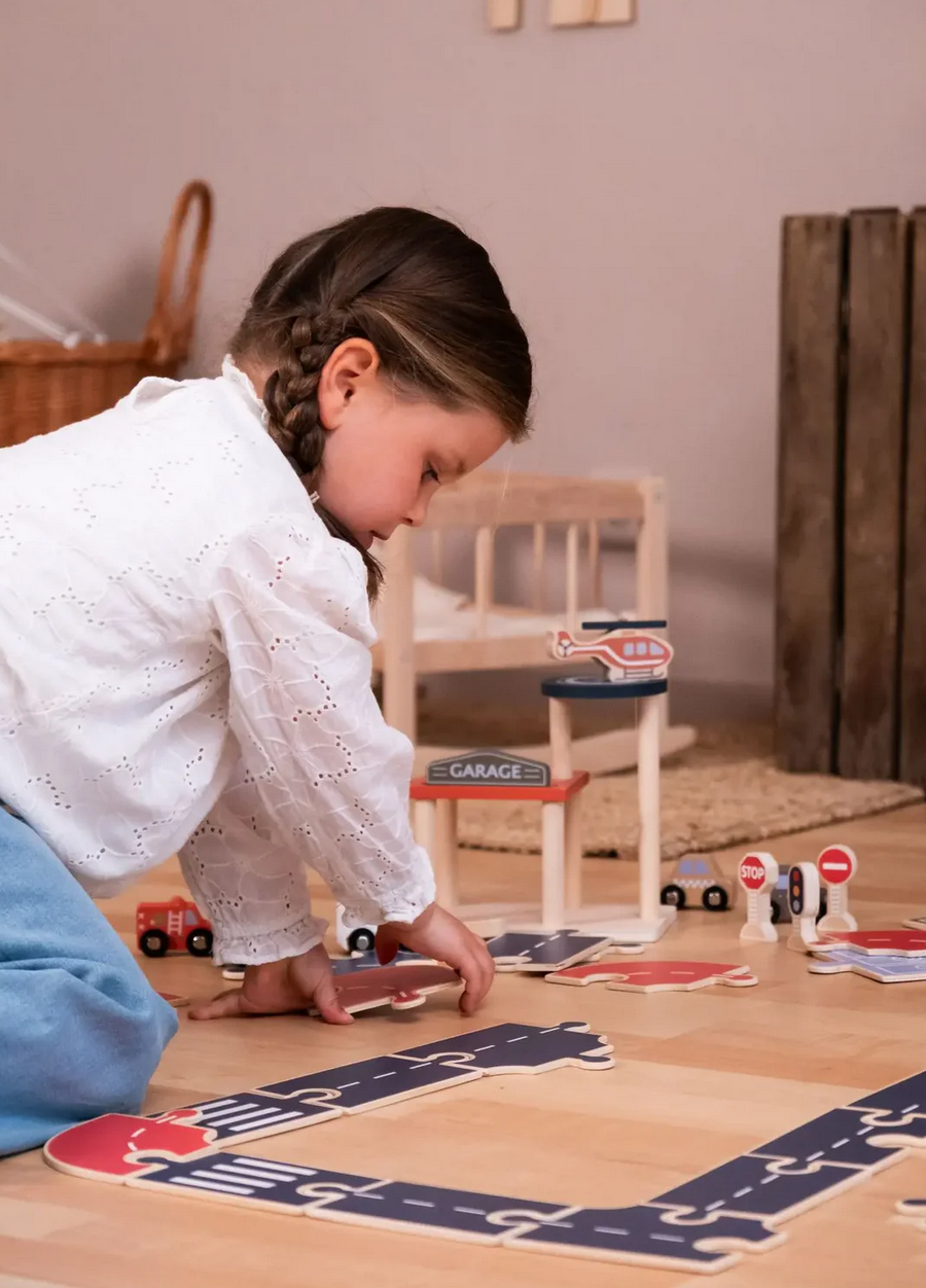 Child playing with toy cars on a wooden floor