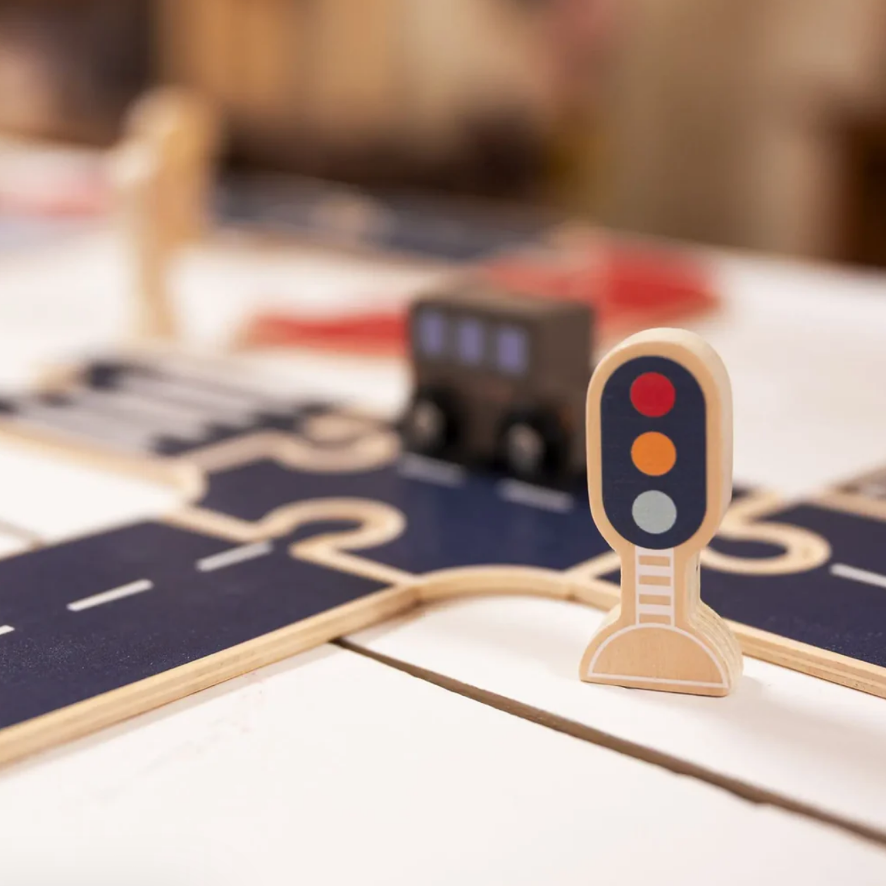 Wooden toy traffic light on a wooden road track with a blurred background