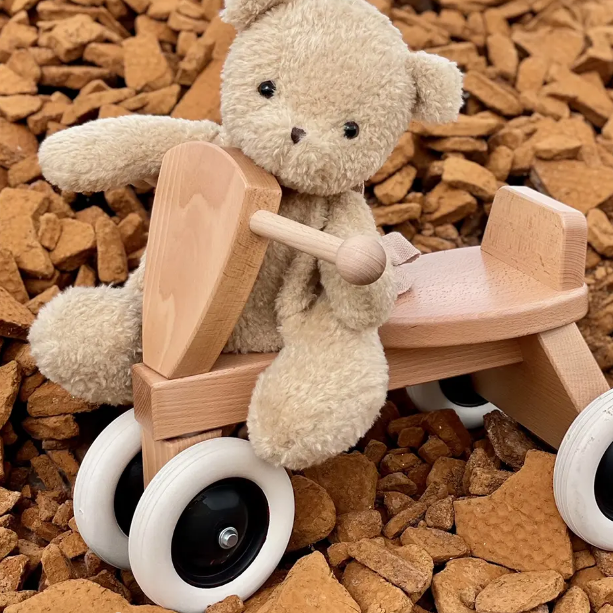 Teddy bear on a wooden tricycle surrounded by wooden blocks