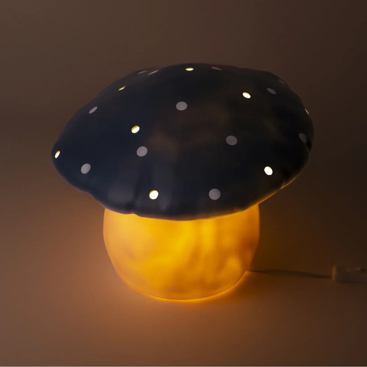 Mushroom-shaped night light with black cap and yellow stem on a dark background